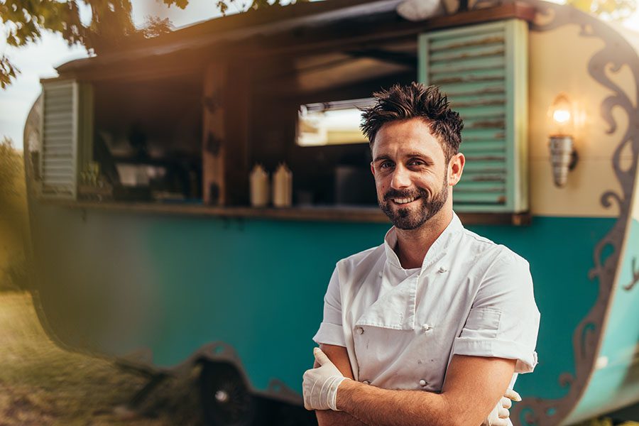 Food Truck Insurance - Portrait Of Happy Food Truck Business Owner Standing In Front Of His Food Truck